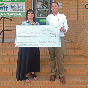 Tami Daniel-Means of Targets & Tiaras presents a $19,000 check to Athens Habitat executive director Spencer Frye