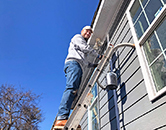 Volunteer on ladder painting exterior of house